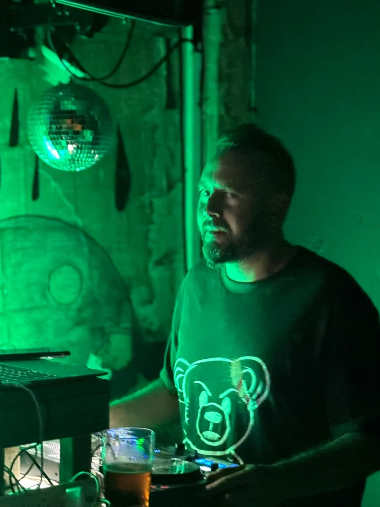 DJ Nimi at the decks under green lighting